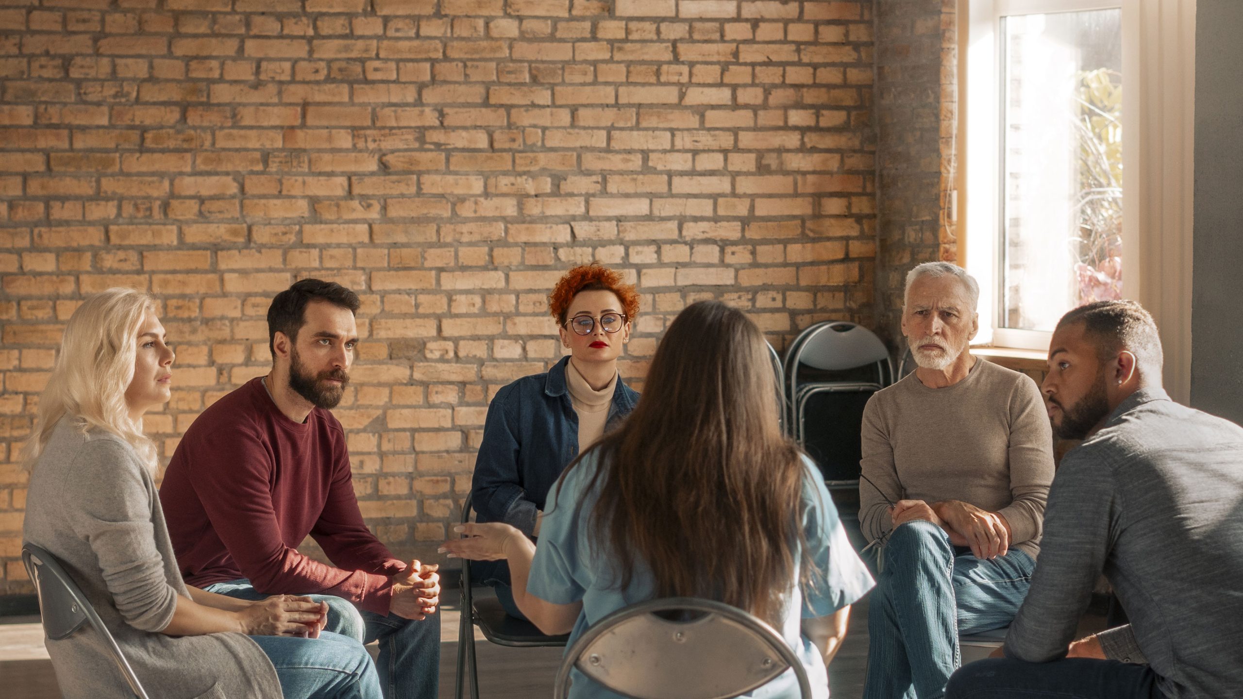 A group of people in a room listening to one person speak