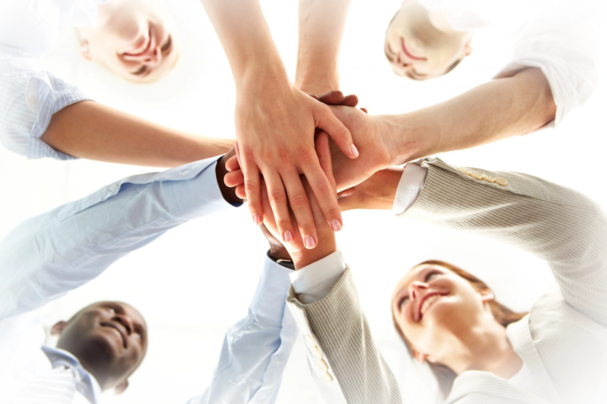 looking upwards to four people in a circle with their outstretched hands together