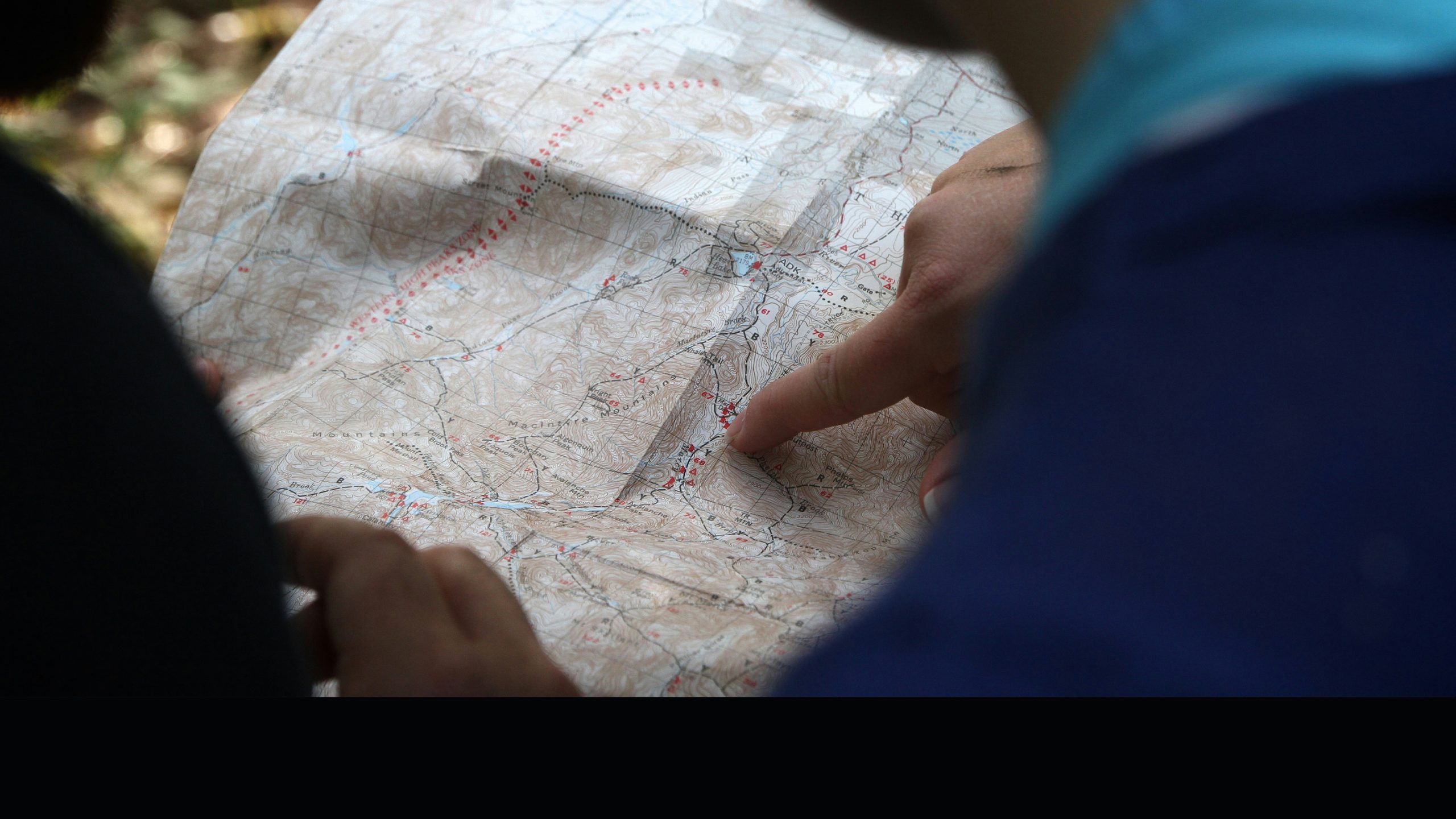 a person's hand pointing to a location on a map