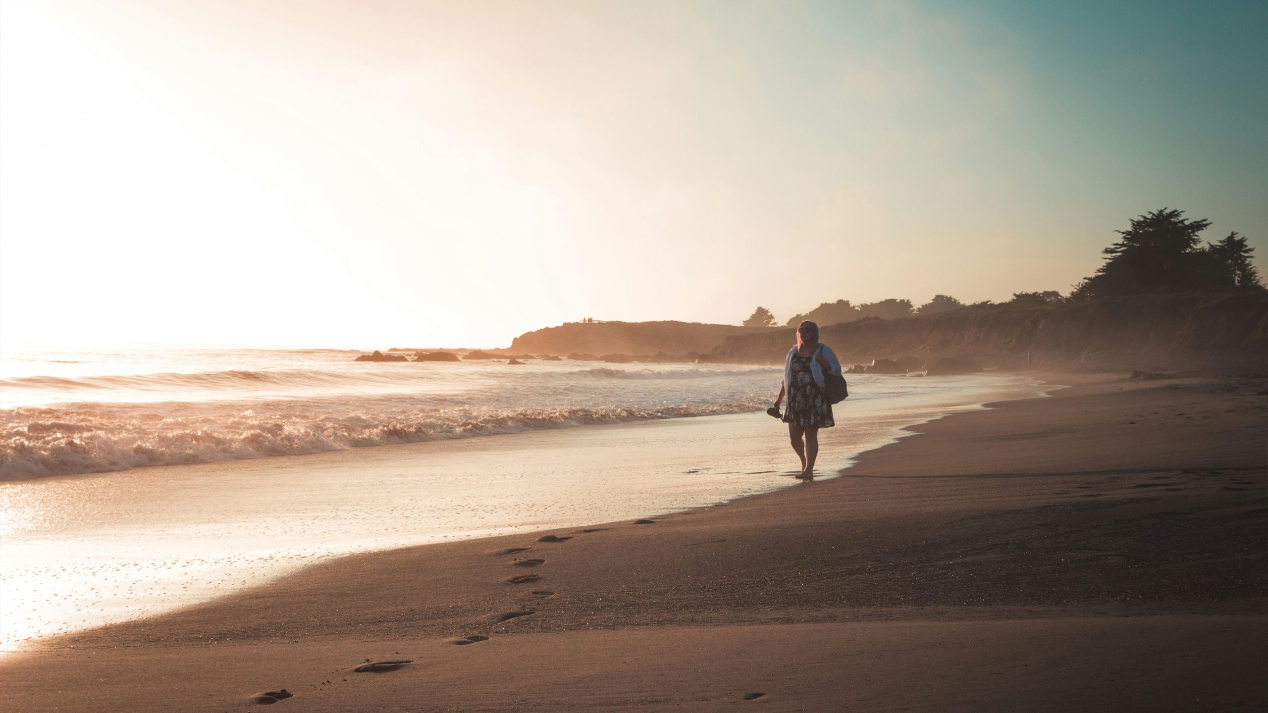 A woman walking on a beach at dusk