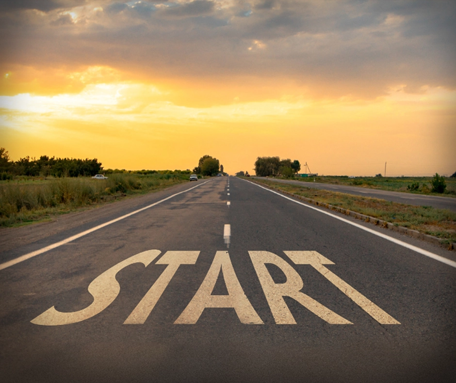 The word start painted on a road which leads off into the sunset