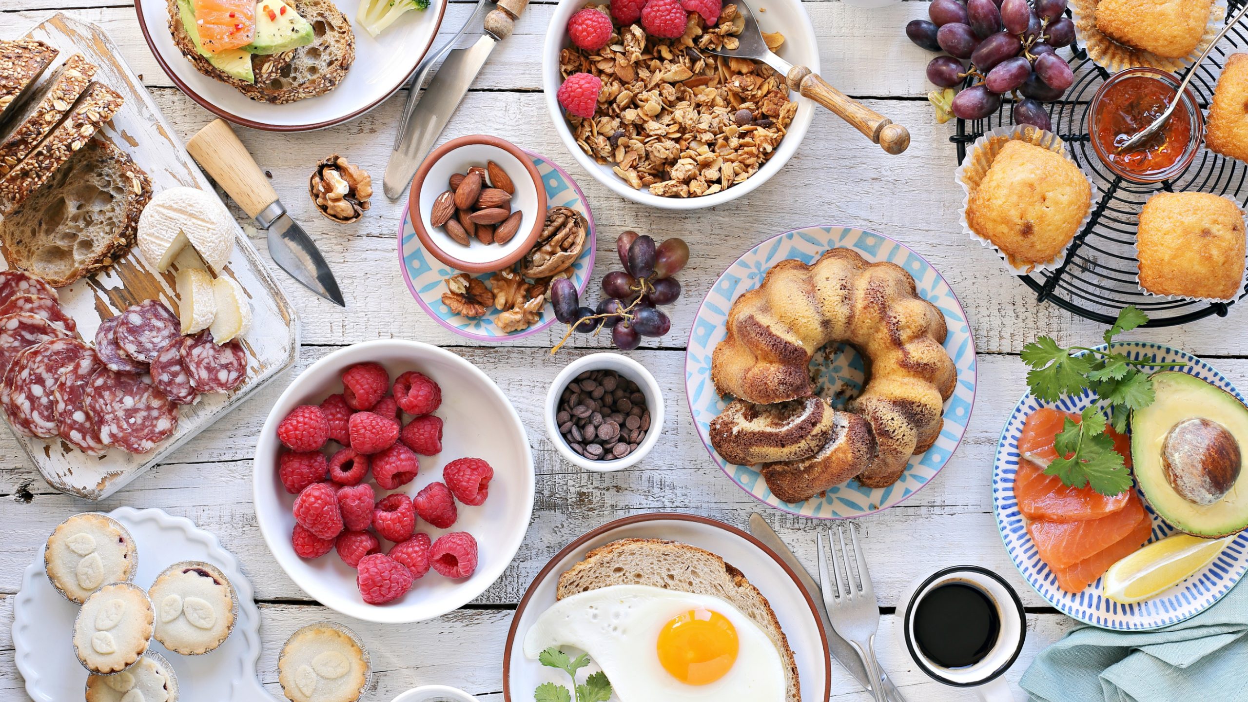 a white painted wooden table covered with plates of fresh produce and baking